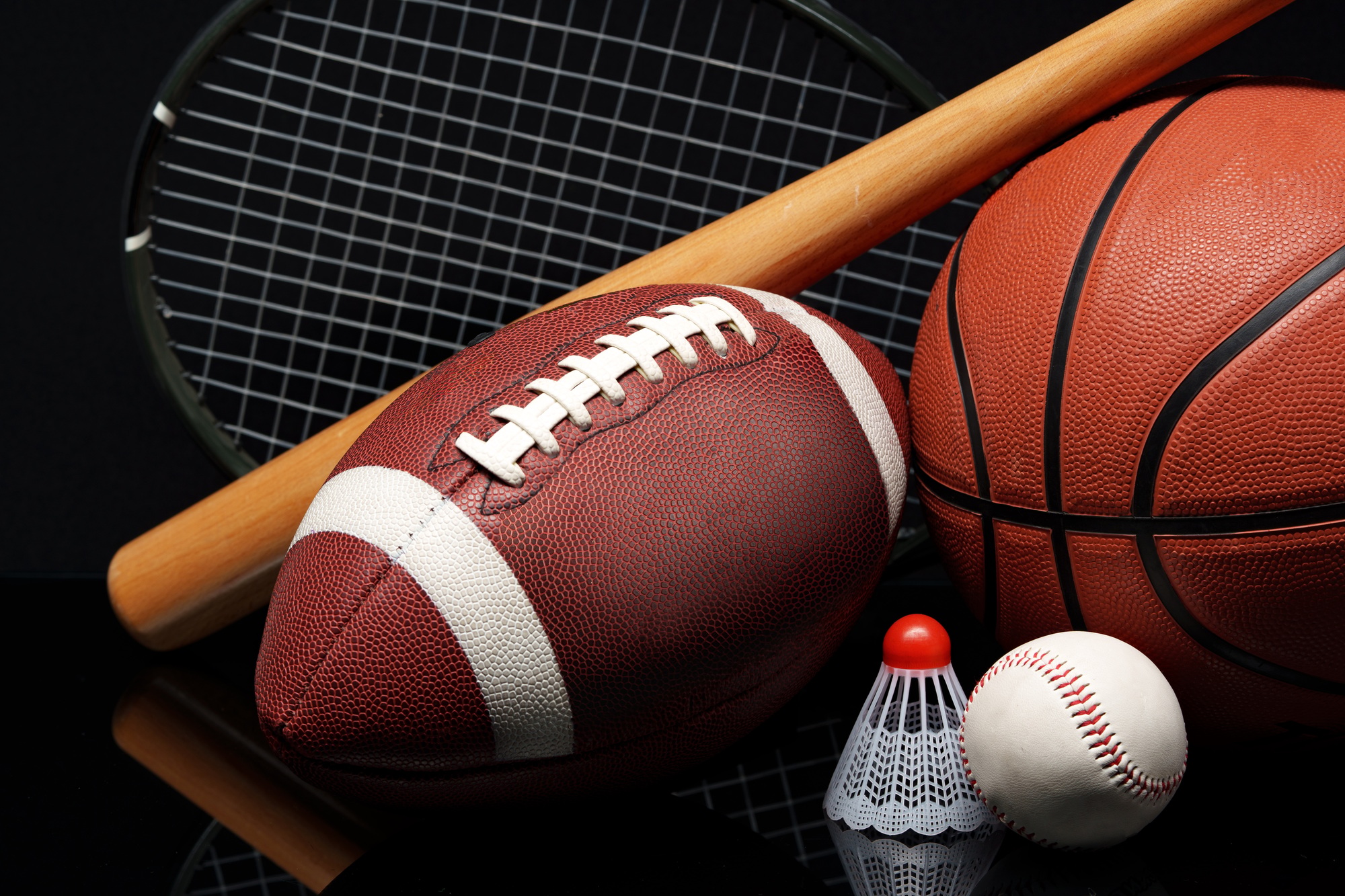 Various sports equipment on black background studio shot